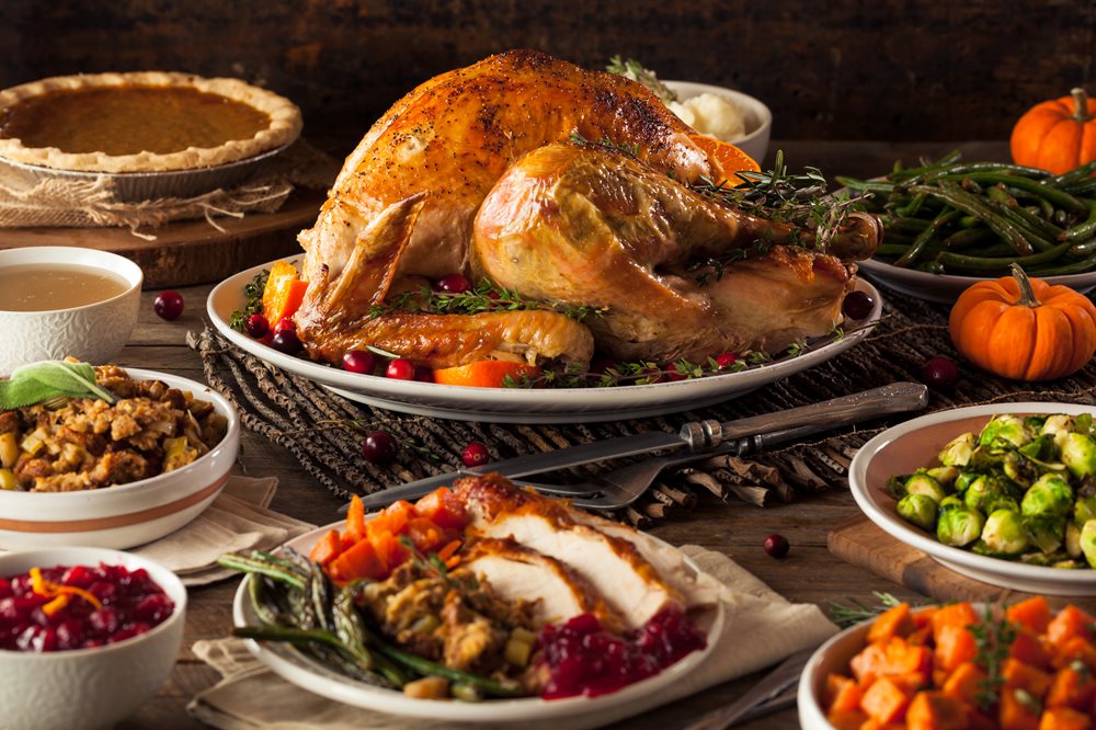 A closeup of a Thanksgiving feast, complete with a golden turkey and all the sides.